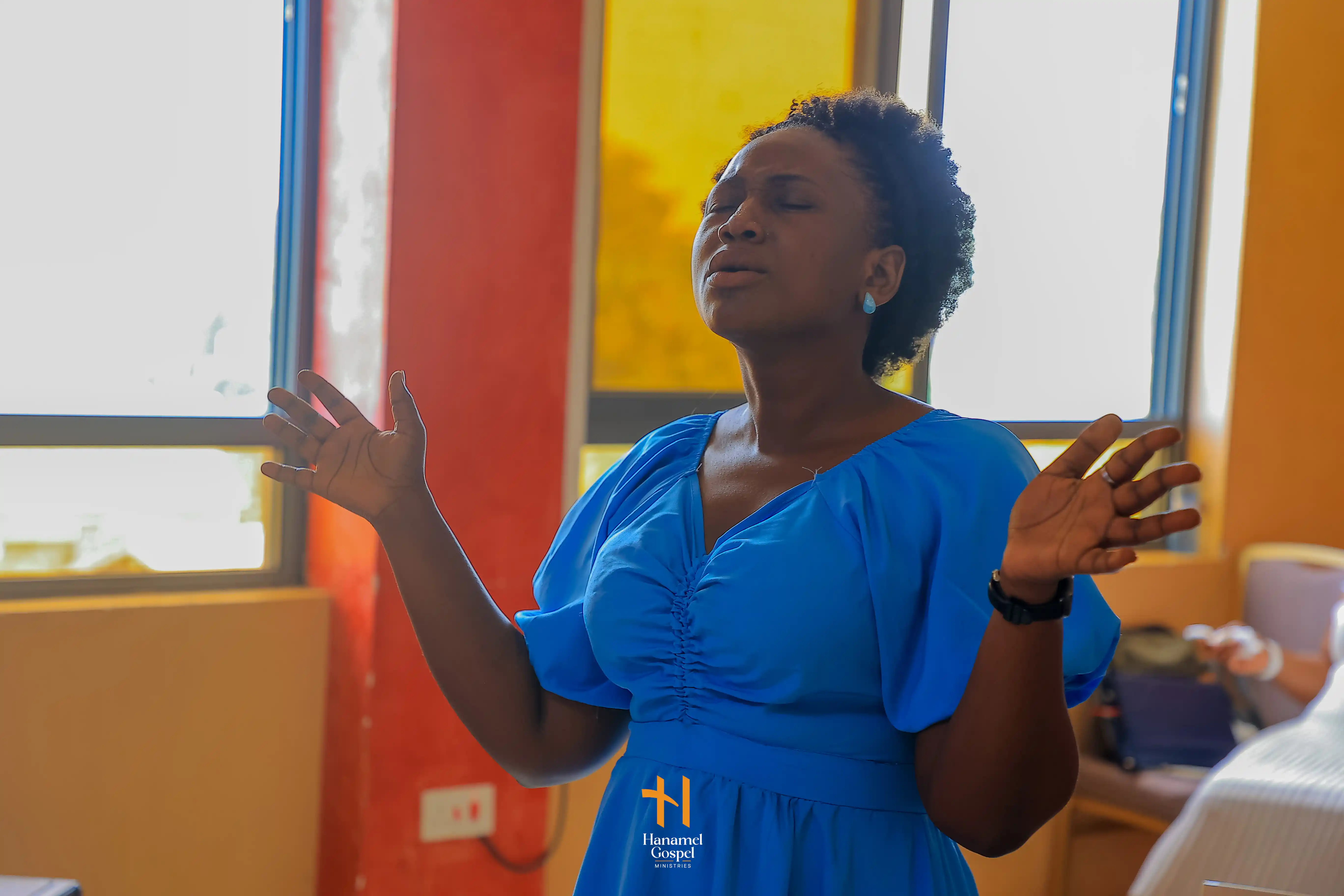 A worshipper lifts her hands at Hanamel Gospel Ministries